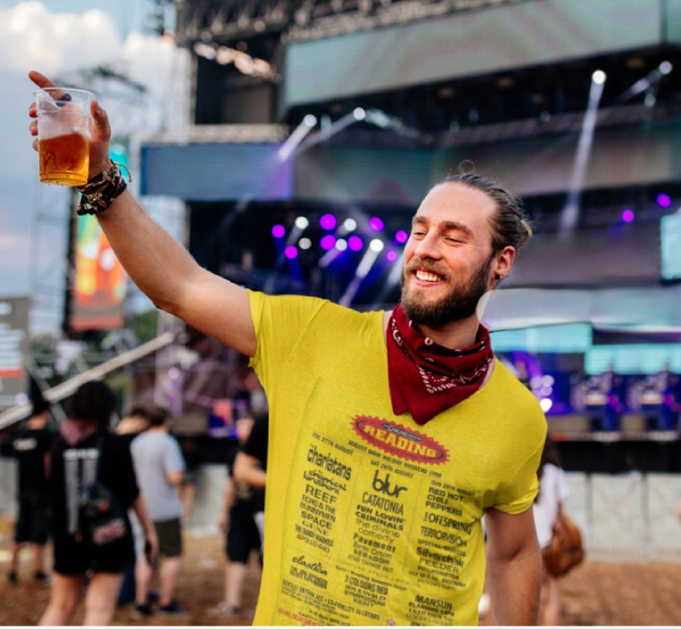 Man holding a beer smiling at a Festival wearing festival tshirt